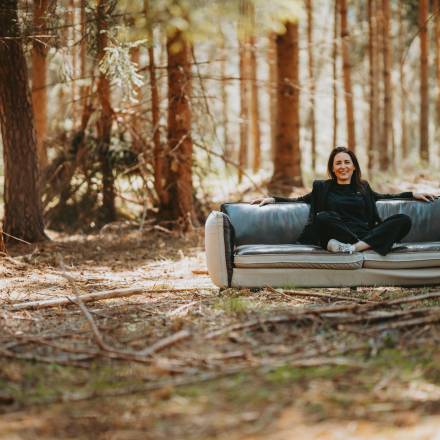 Frau sitzt auf einer Couch im Wald