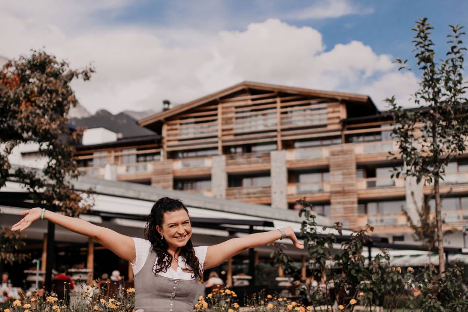 Mitarbeiterin des Alpenresort Schwarz sitzt auf Steinbank vor dem Resort
