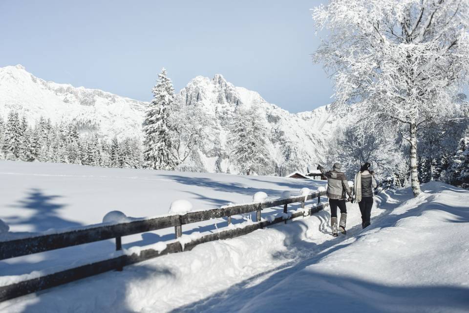 Paar spaziert händchenhaltend im Schnee in Tirol