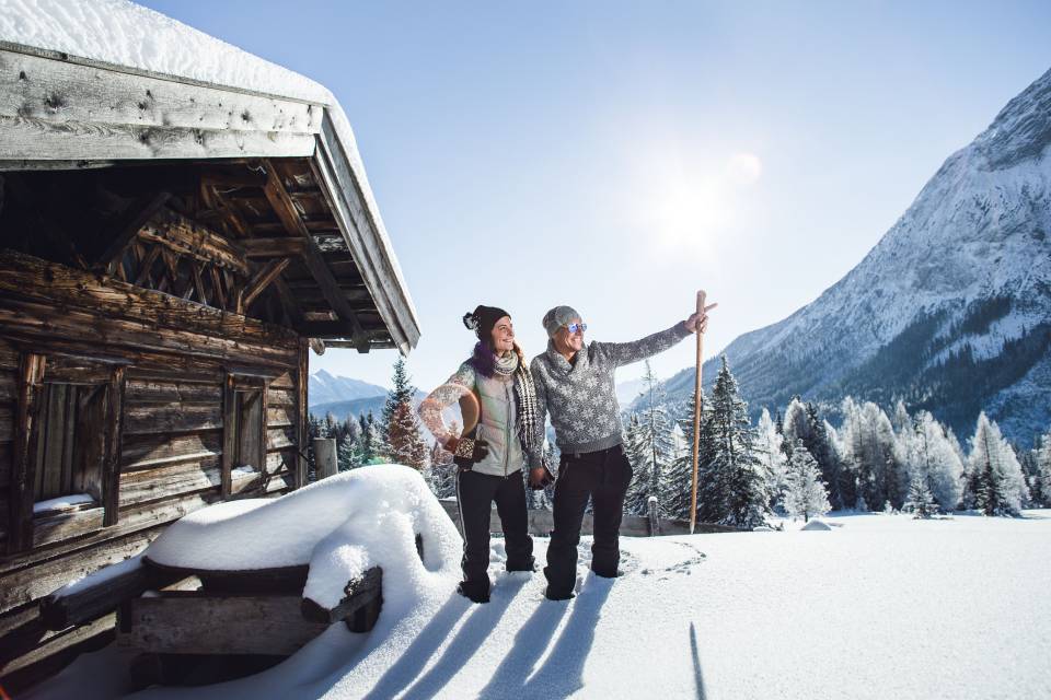 Paar steht im Schnee auf der Alm