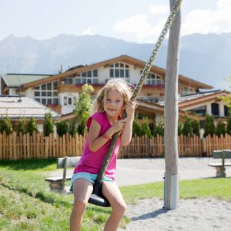 Kind auf Schaukel vor dem Alpenresort Schwarz