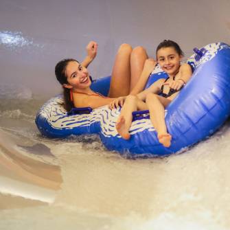 Kinder rutschen auf Reifen eine Wasserrutsche herunter