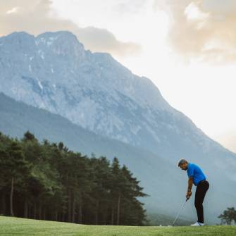 Golfer beim Abschlag mit den Tiroler Alpen