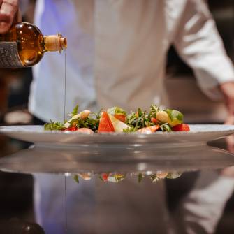 Koch gießt Öl über einen Salat