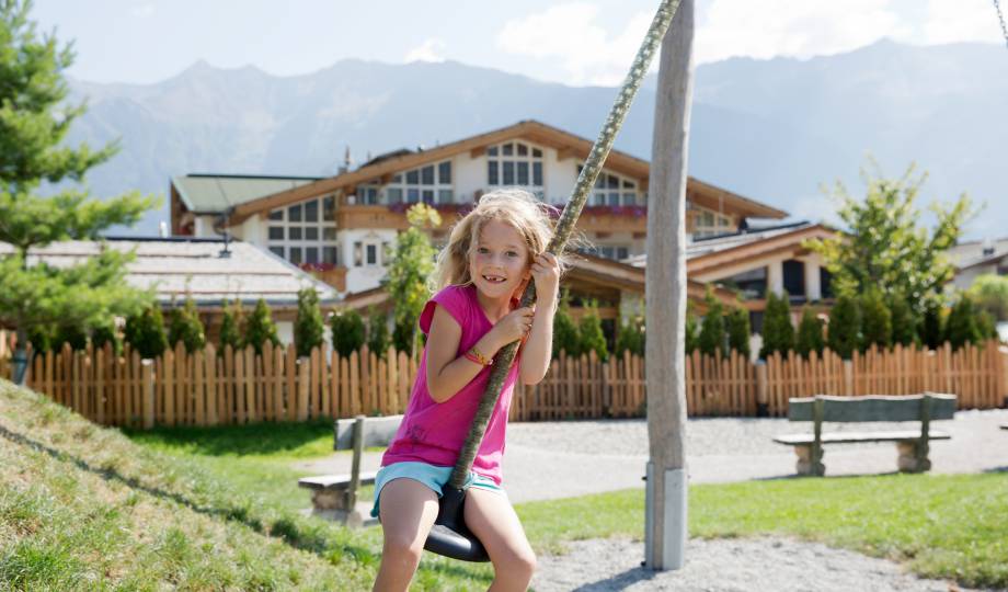 Kind auf Schaukel vor dem Alpenresort Schwarz